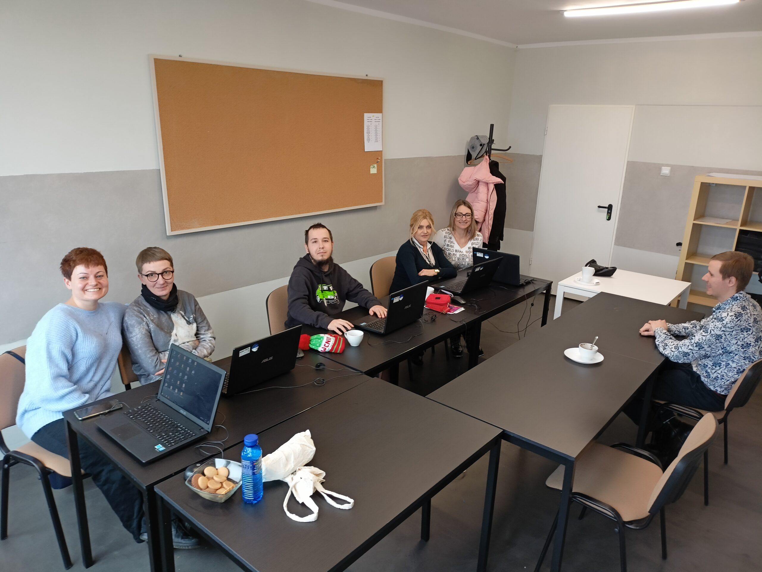 Projekt "Bez przeszkód" zajęcia komputerowe w sali w IB Polska w Tychach - grupa siedzi przy stole z prowadzącymi