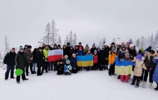Zdjęcie grupowe uczestników wycieczki w Zakopanem. Dzieci trzymają flagi Polski i Ukrainy.