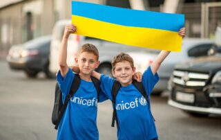 Dwóch chłopców trzymających flagę Ukrainy. Zdjęcie pochodzi z Twittera UNICEF Ukraine
